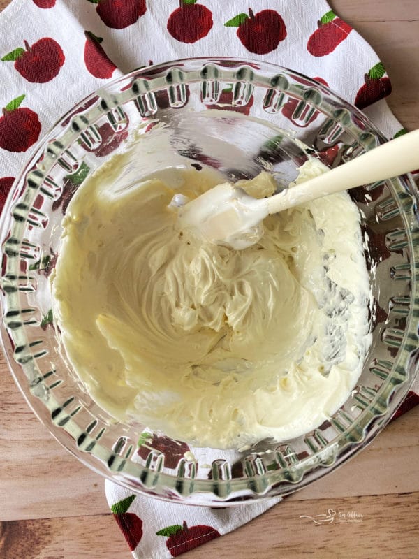 fluffing cream cheese and marshmallow fluff in bowl with rubber spatula
