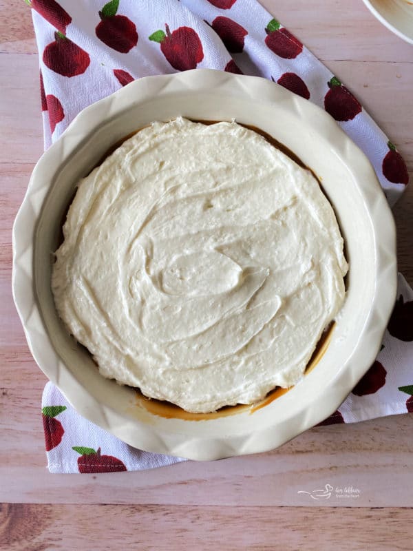 spreading cream cheese in pie plate on top of caramel