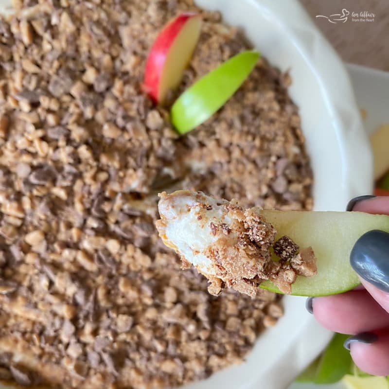 top view of caramel apple dip topped with Heath bits with apple slices