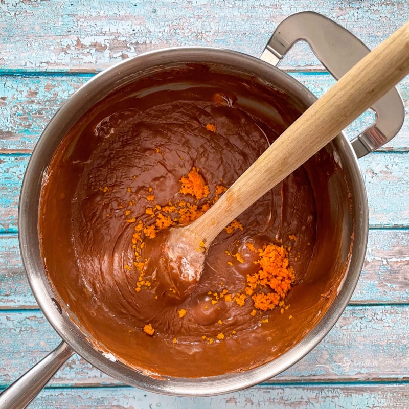 mixing orange zest in saucepan with wooden spoon and fudge