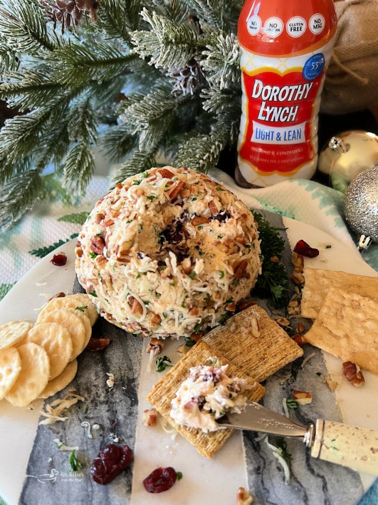 Dorothy's Holiday Cheese Ball plated with hoiiday decorations and a bottle of Dorothy Lynch