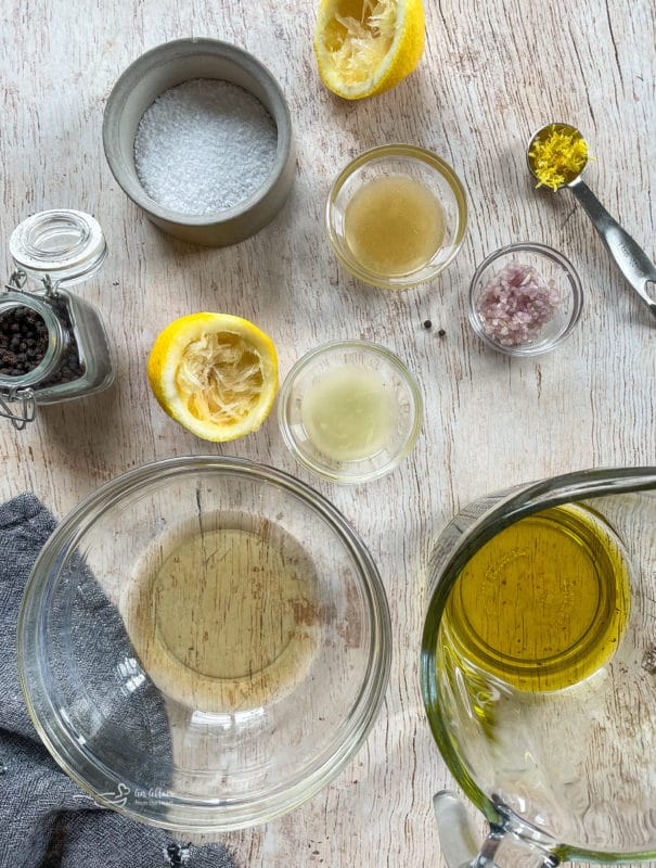 vinaigrette ingredients in bowls on wooden surface with oil and citrus
