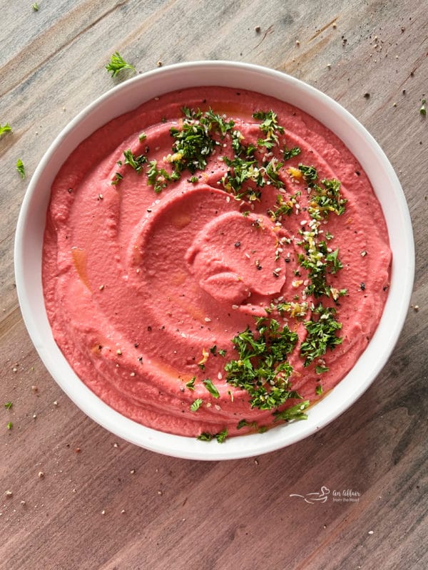 white bowl with beet hummus and parsley