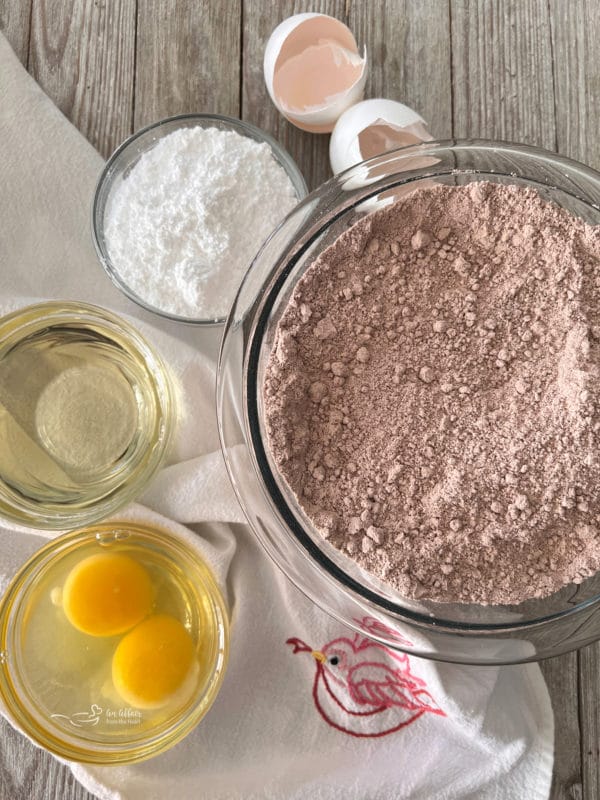 bowl of cake mix with bowls of oil, eggs, sugar