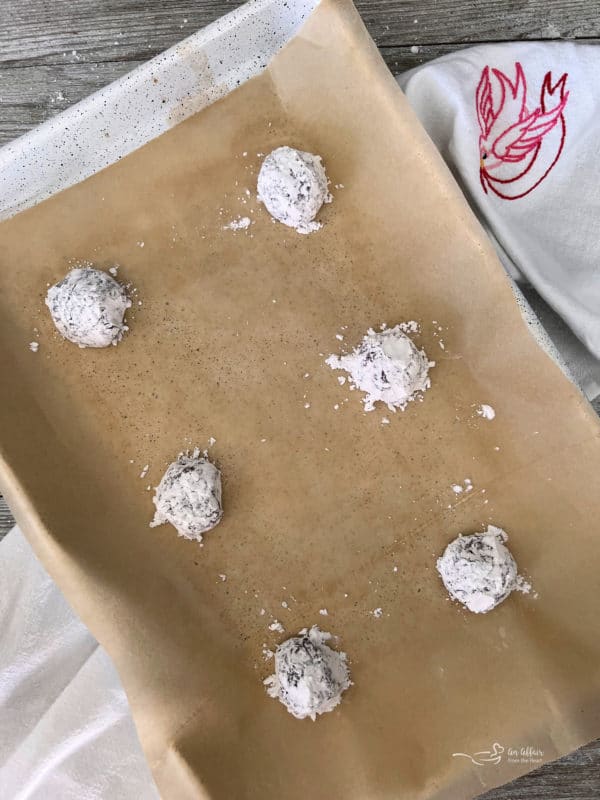 red velvet cookie dough with powdered sugar in baking sheet