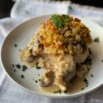 baked pork chop on plate with stuffing and herbs on top with mushroom gravy