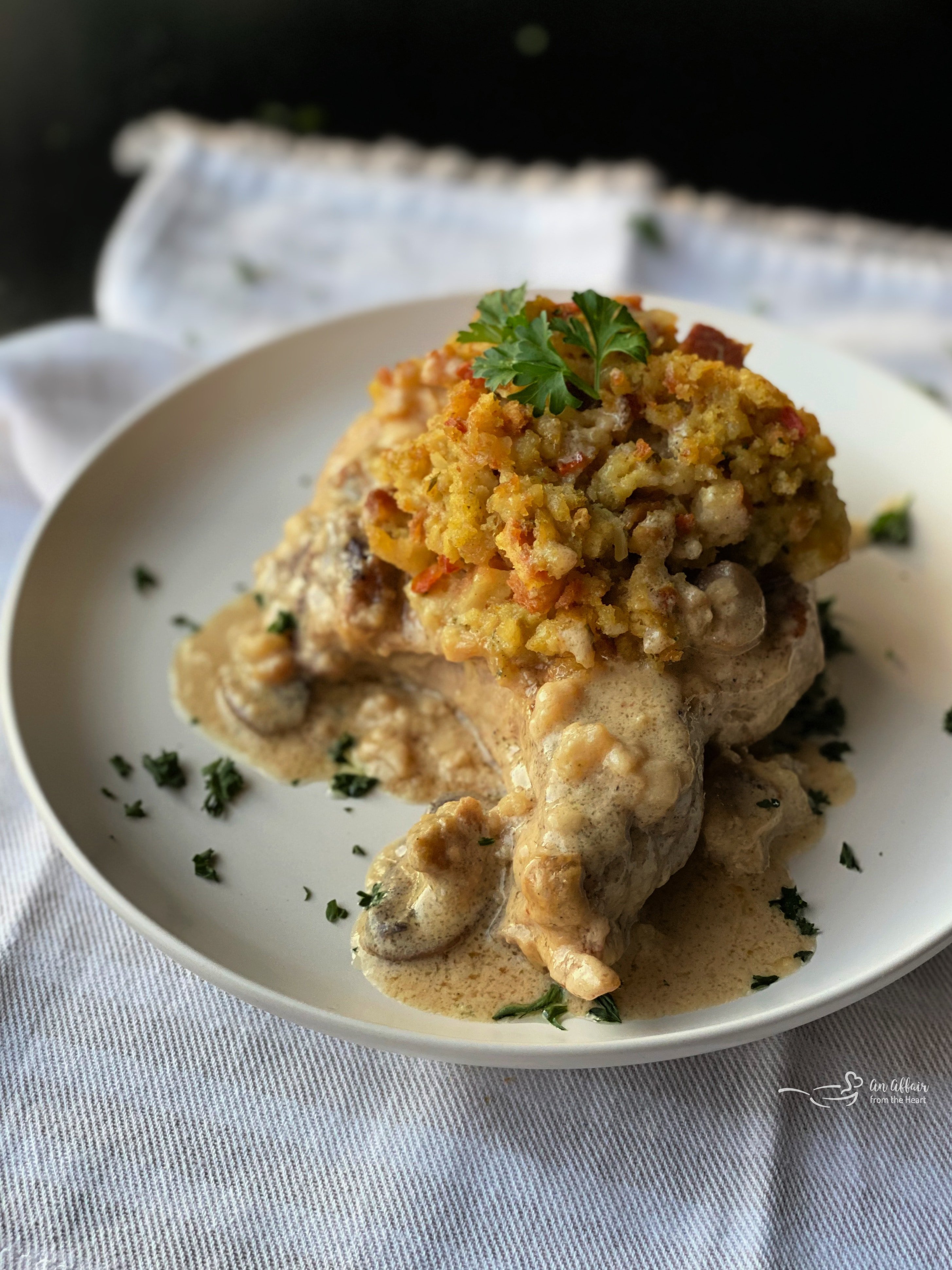 baked pork chop on plate with stuffing and herbs on top with mushroom gravy
