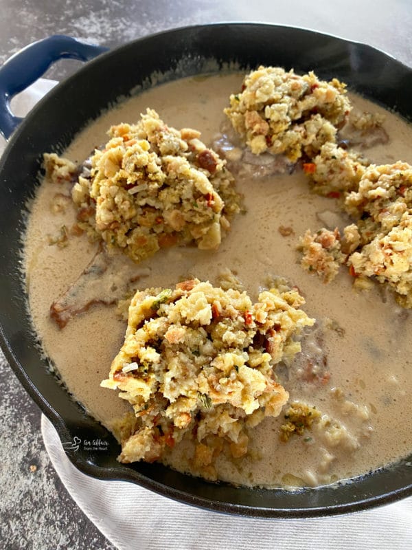 cooked pork chops in skillet with stuffing and gravy