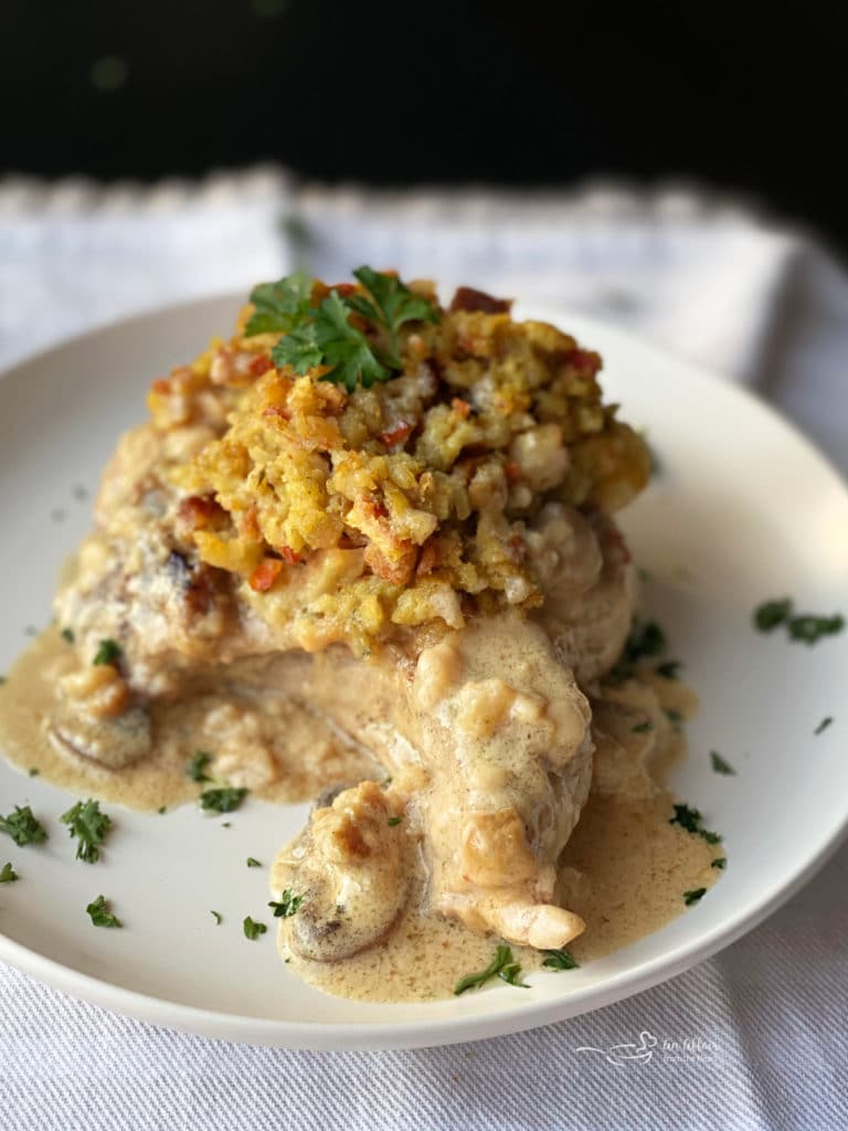 white plate with baked pork chop with stuffing and gravy