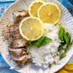 one plate with chicken breast, rice, lemon, rosemary, and basil