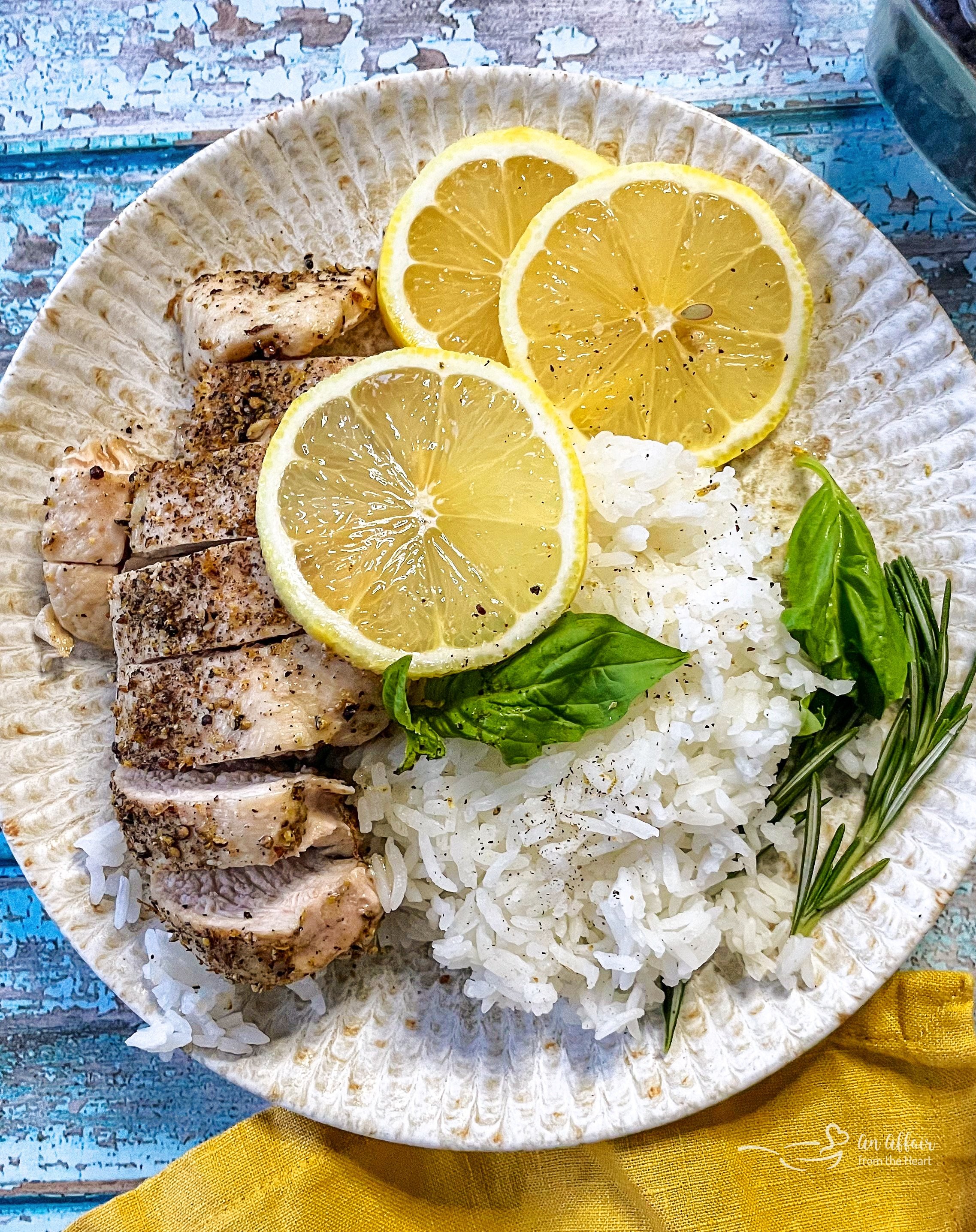 one plate with chicken breast, rice, lemon, rosemary, and basil