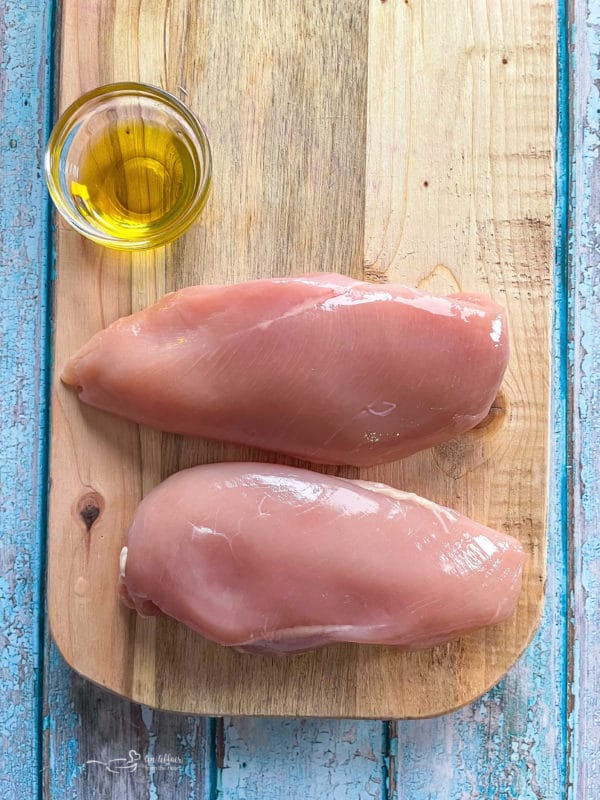 two chicken breasts on cutting board with oil