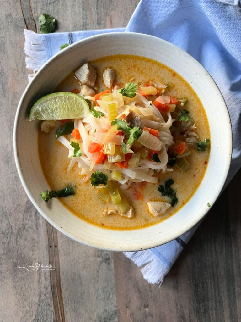 white bowl with Thai chicken noodle soup and lime