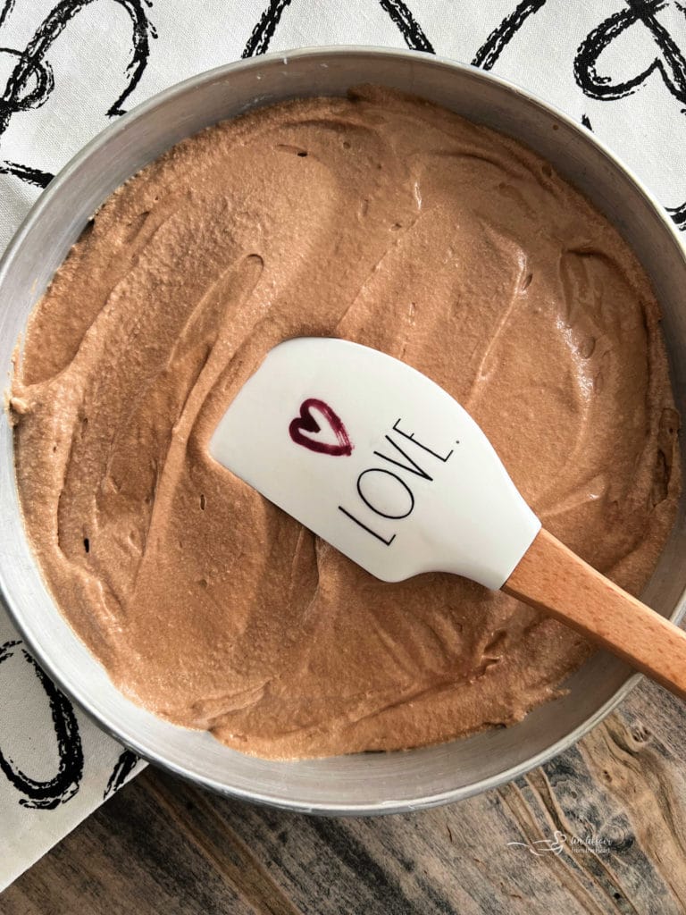 spreading chocolate cake batter in pan with rubber spatula