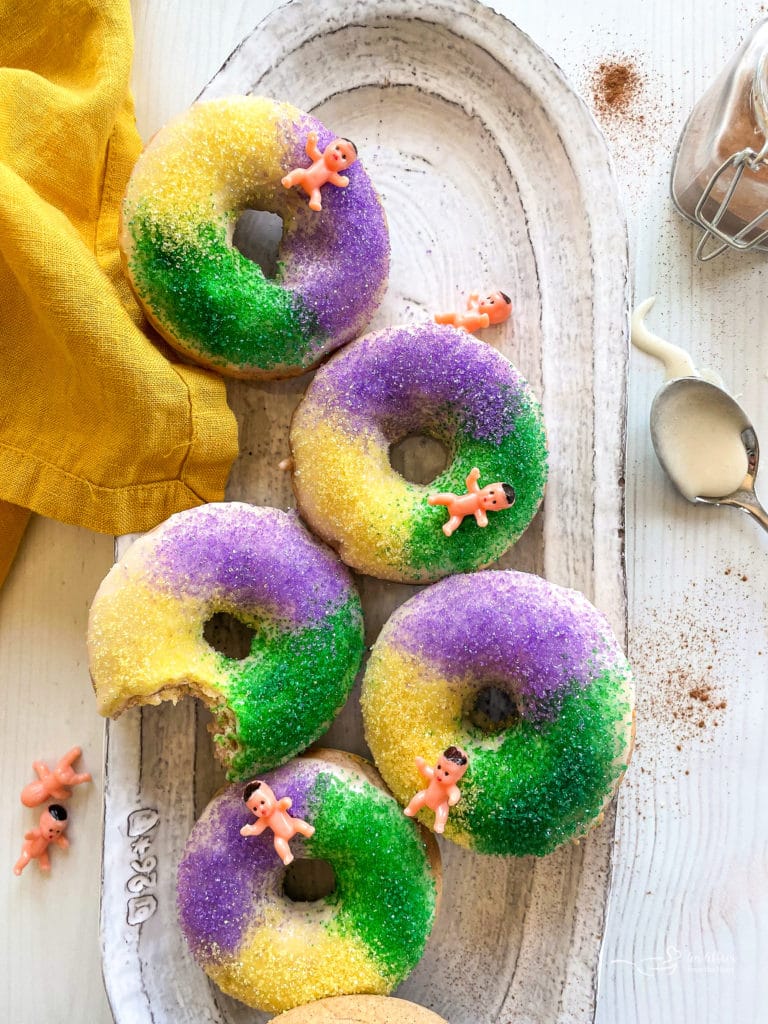 King Cake Baked Donuts arranged n a platter with a gold napkin