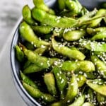Extreme close up of air fryer edamame beans in a white bowl.