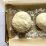 Rolled dough balls on a parchment lined baking sheet.
