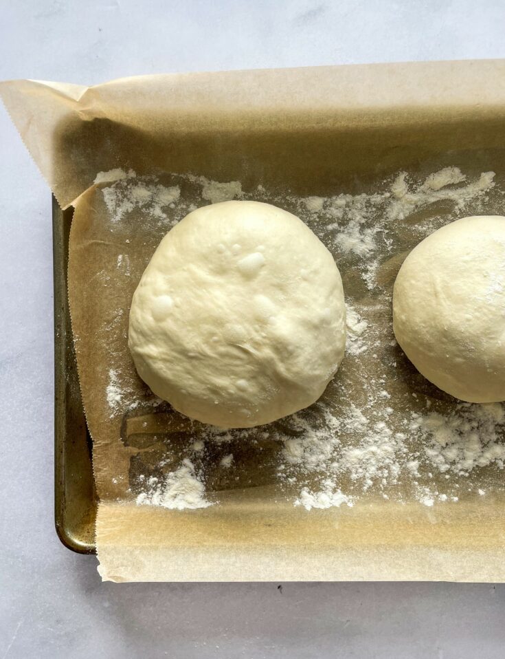 Rolled dough balls on a parchment lined baking sheet.