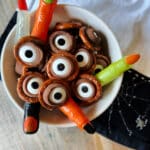 rolo pretzel eyeballs and plastic witches fingers in a white serving bowl.