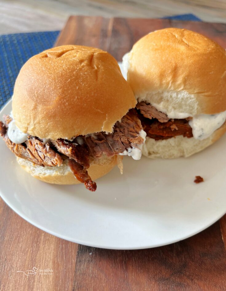 Two spicy beef sliders on a white plate.