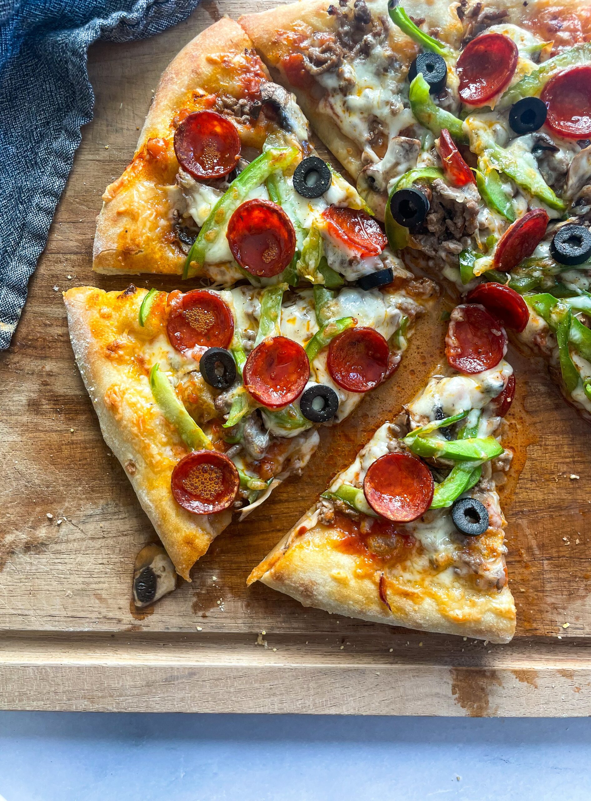 Supreme pizza slices on a wood board.