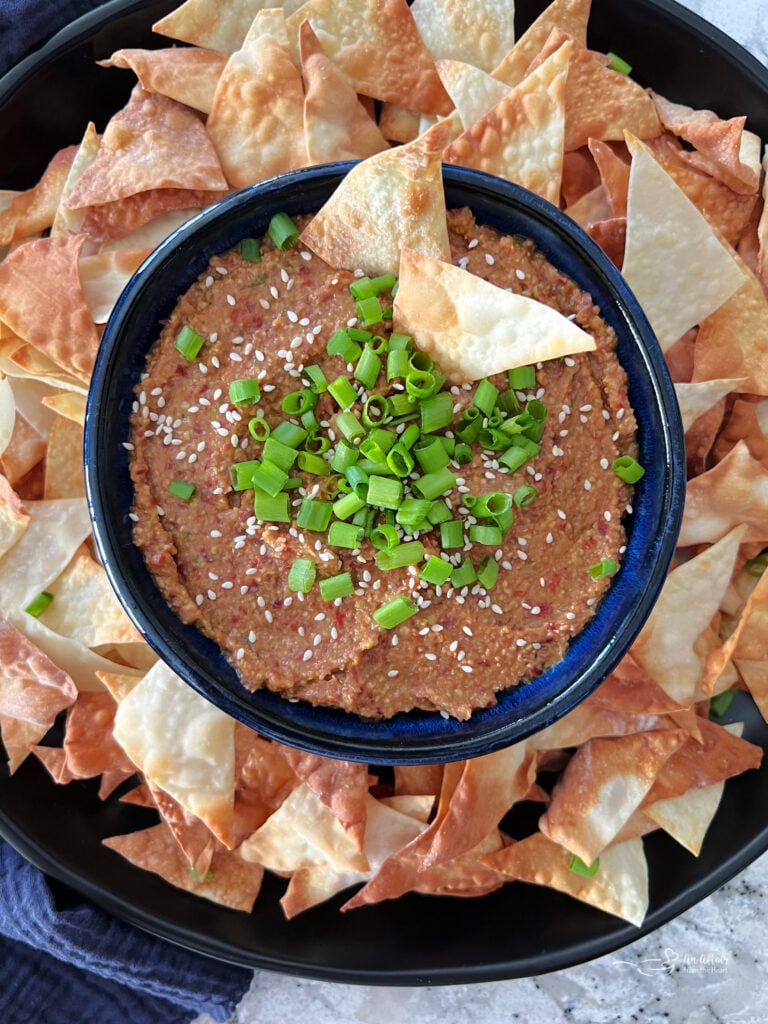 Asian bean dipped topped with green onions in a blue bowl.