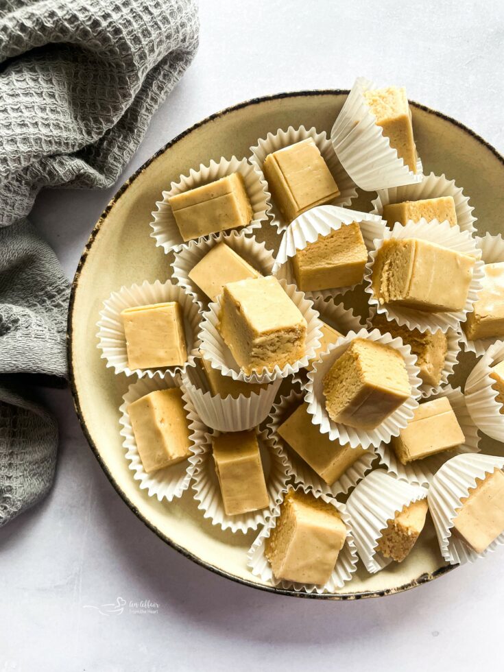 Peanut butter fudge stacked on a cream color dish.