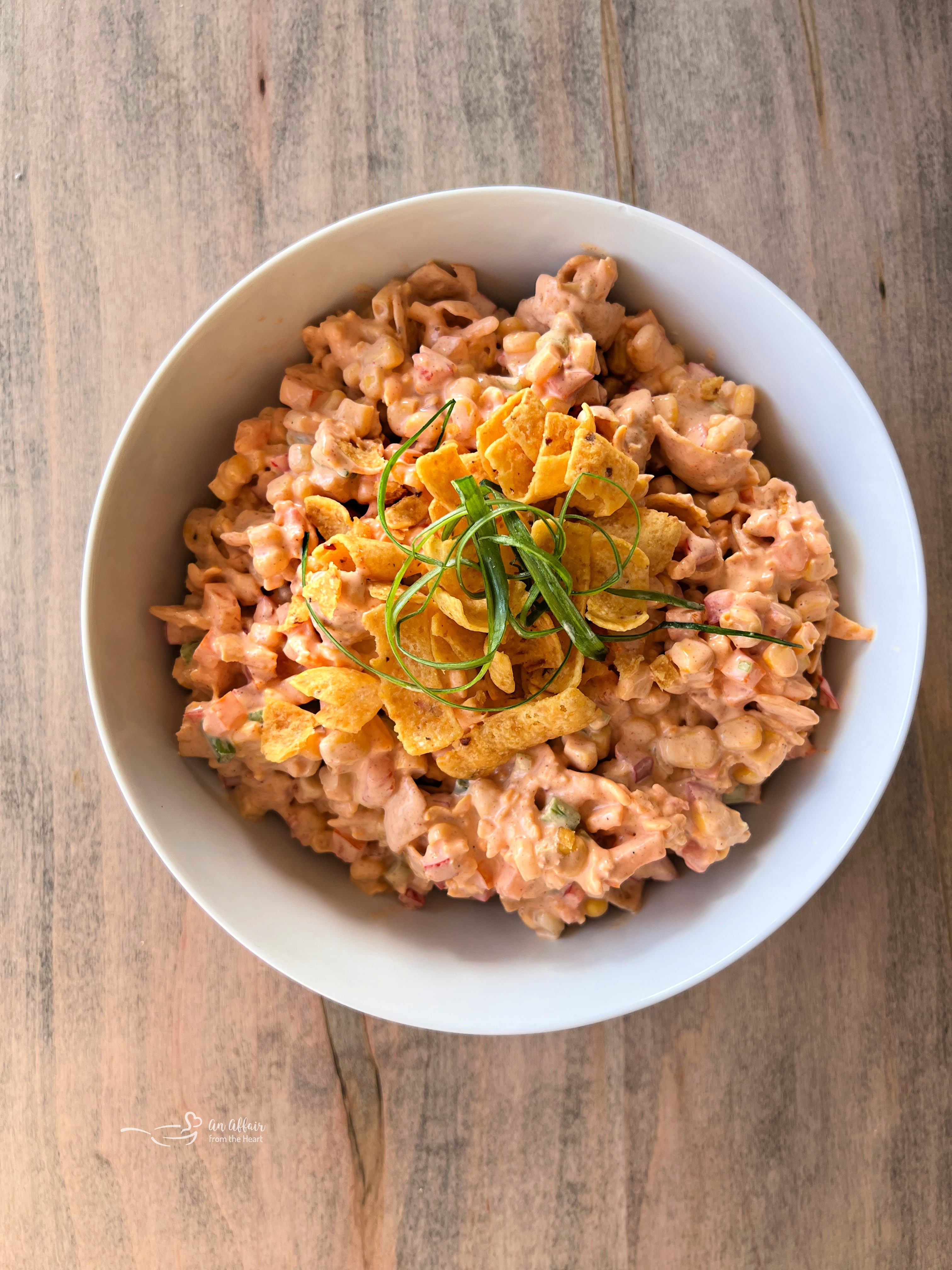 Fiesta Frito Corn Salad 11 Delicious Frito Corn Salad served in a white bowl with a vintage spoon, ready to eat