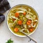 Close up of Homemade Chicken Noodle Soup and a spoon in a white bowl.