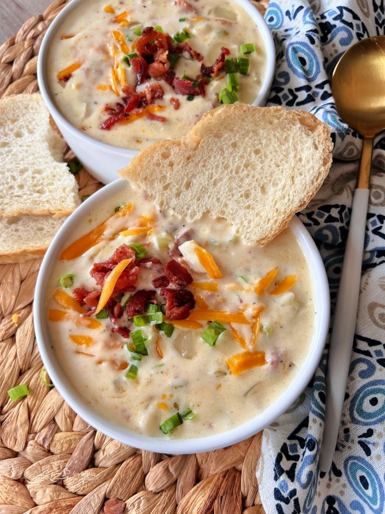 Close up of a bowl of Creamy Bacon soup topped with a piece of bread on the side of the bowl.