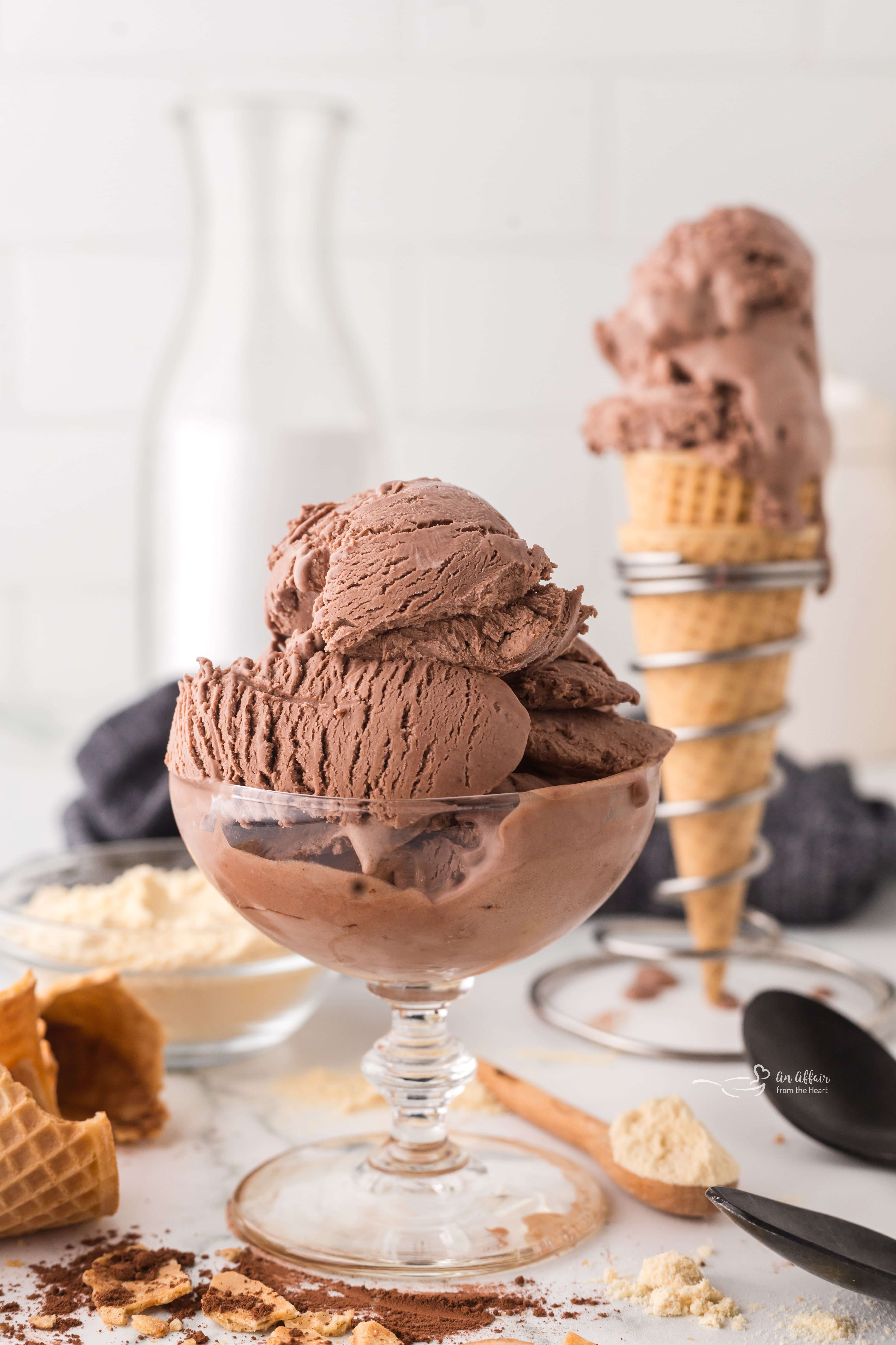 A large serving bowl full of Chocolate malt ice cream with a waffle cone full in the back.