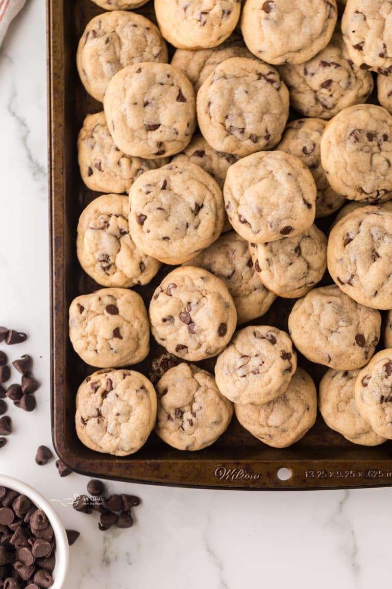 Mini Chocolate Chip Cookies stacked on a sheet pan